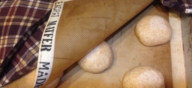 three rounds of pizza dough showing between two silpats