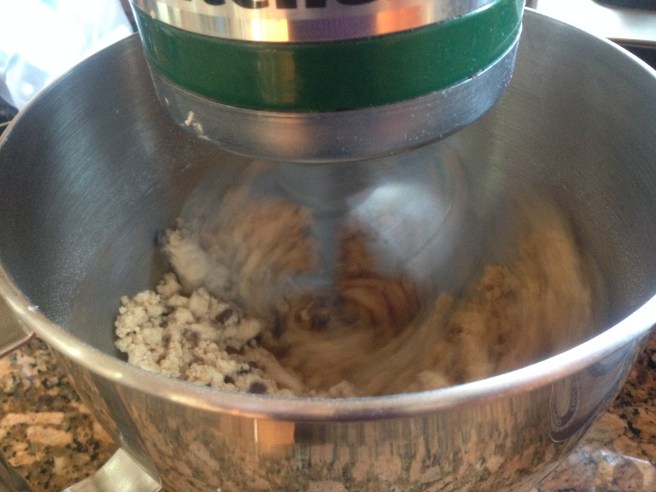 dough forming pea-sized clumps being mixed in green kitchenaid mixer