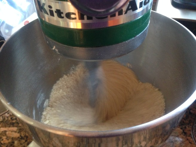 sandy mix of flour and butter being mixed in a green kitchenaid mixer